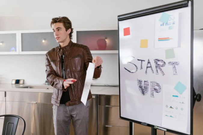 A startup founder presenting a pitch on a flip chart during an investor meeting.